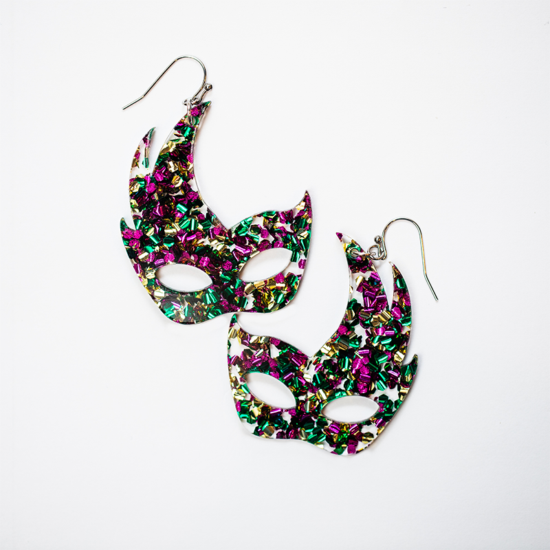 Glittering carnival mask-shaped earrings with vibrant purple, green, and gold confetti pattern.